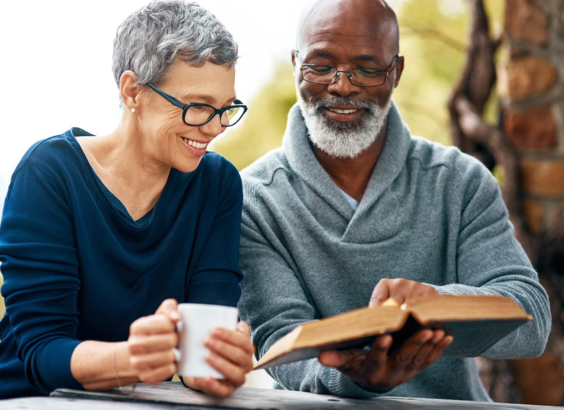 Medicare - Cheerful Senior Couple Read a Book Together Outside